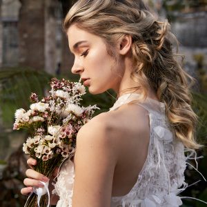 Woman with half-up, half-down hairstyle featuring loose curls and twisted sections for an elegant look