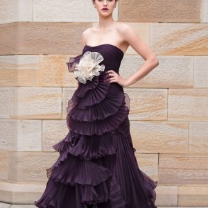 Voluminous updo with teased crown, glamourous event makeup and tiered ruffles of elegant plum strapless gown